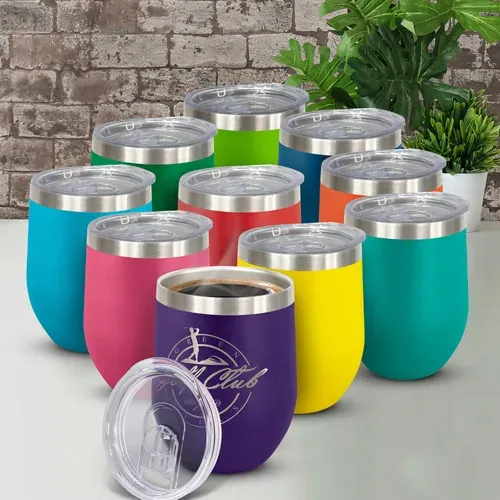 Colourful selection of Cordia Vacuum Cups with clear lids displayed on table against brick wall.