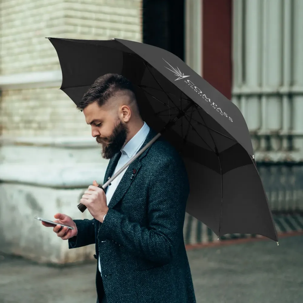 Person holding Hurricane Urban umbrella in black, open profile view with branded panel outdoors