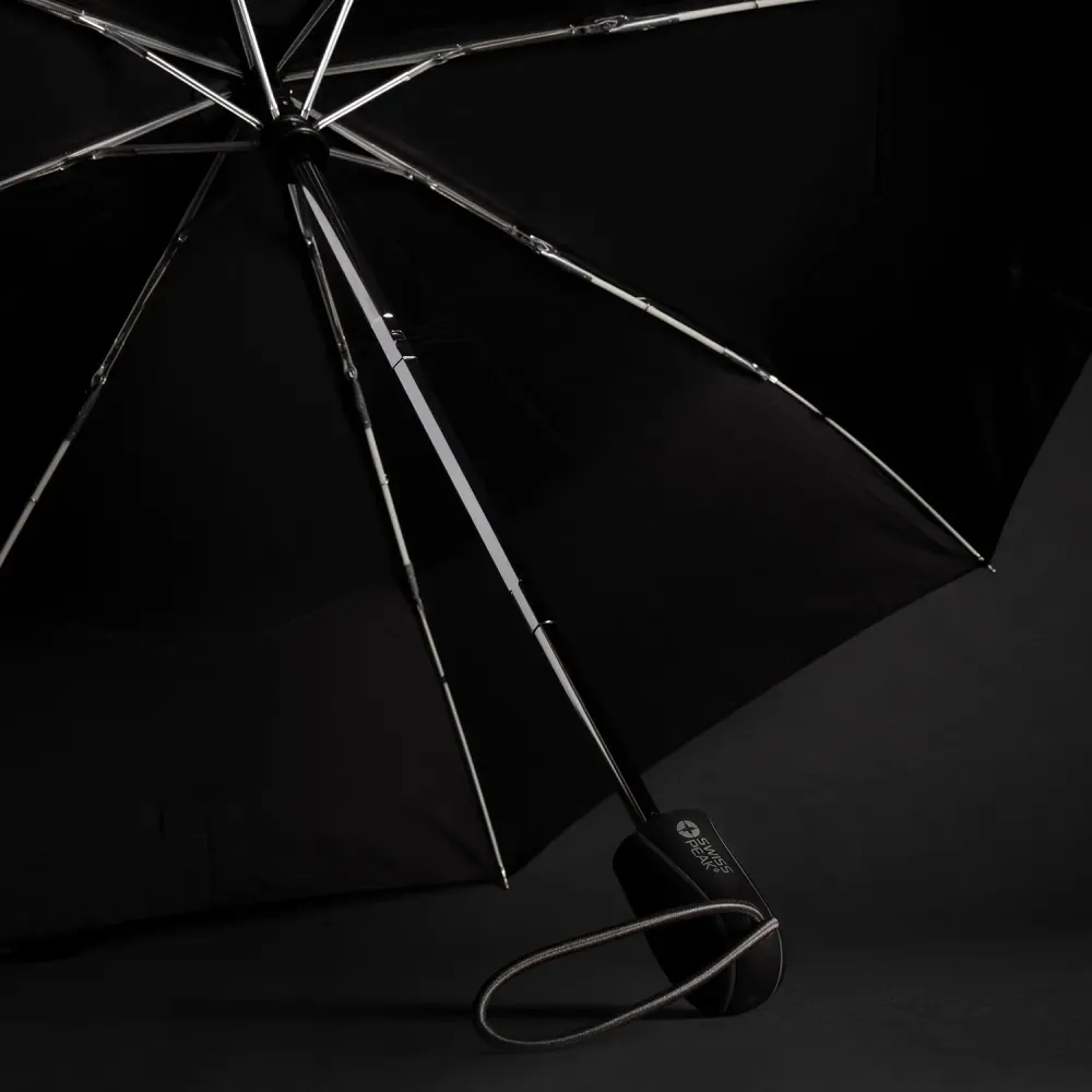 Swiss Peak Traveller Umbrella opened on dark background showing chrome frame, black canopy, and branded handle with wrist strap