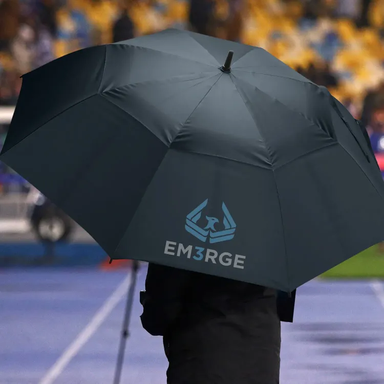 Person holding navy Adventura Sports umbrella with branded panel at outdoor sports venue.
