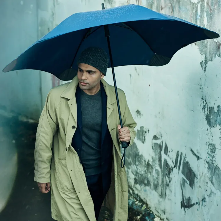 Person walking in rain holding BLUNT Exec umbrella in midnight navy colour