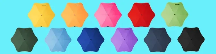 Assorted BLUNT umbrellas displayed top-down in multiple bright colours on blue background