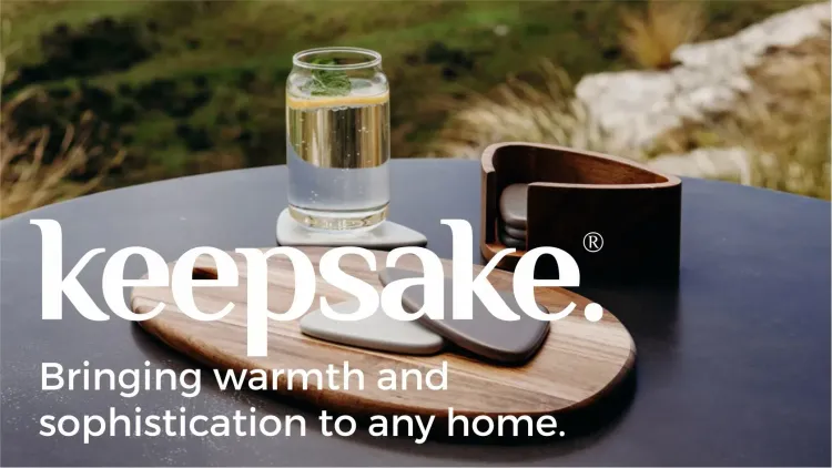 Keepsake logo over table with wooden serving board, coasters and drink glass.