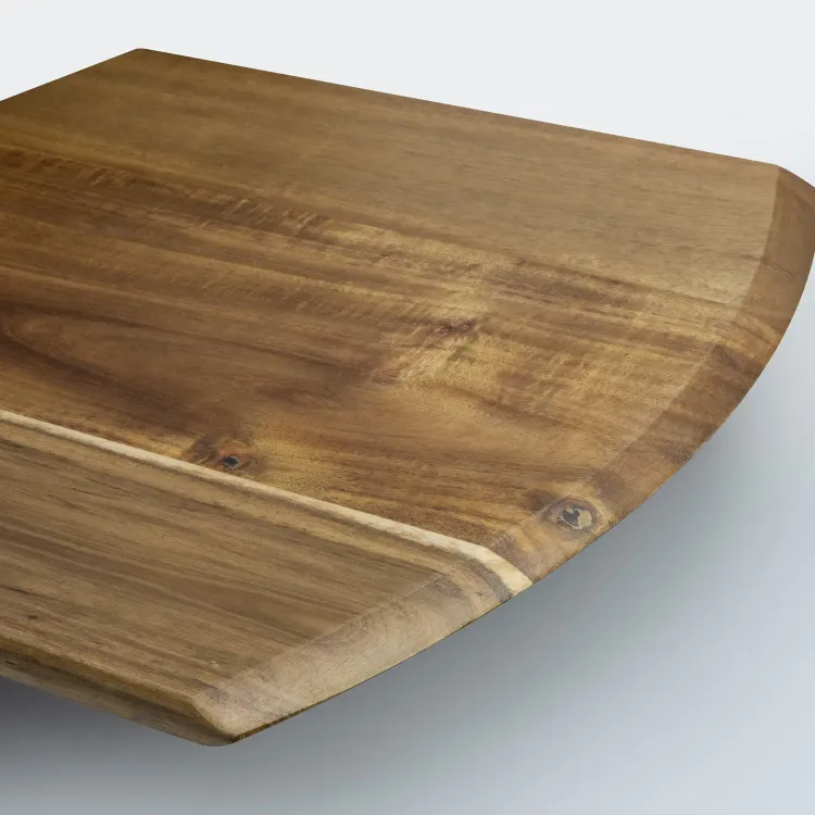 Close-up of acacia wood pizza board showing natural grain and smooth curved edge.
