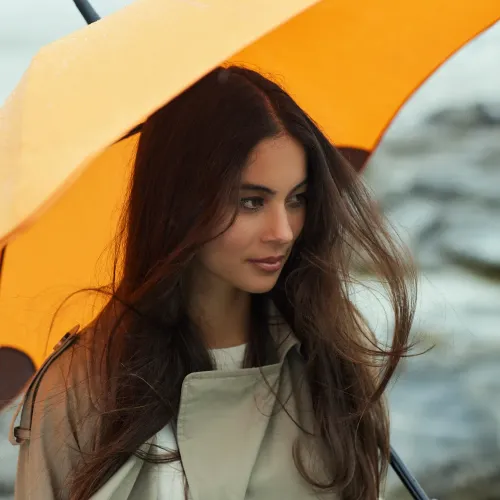 Two women walking in the rain under a BLUNT Classic red umbrella