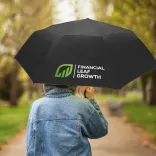 Person walking outdoors holding Hurricane City umbrella in black with branded panel