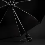 Swiss Peak Traveller Umbrella opened on dark background showing chrome frame, black canopy, and branded handle with wrist strap